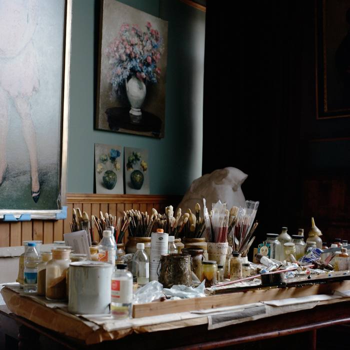 A table of paints with floral studies on the wall