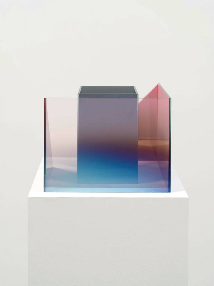 One greyish glass cube within another incomplete pinkish glass cube