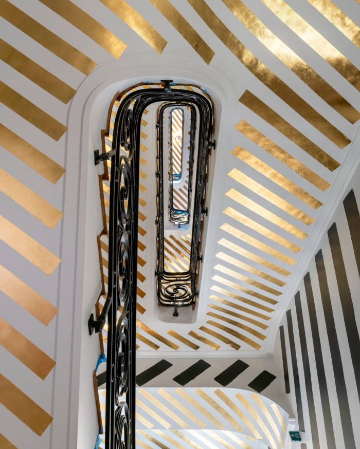 View up a staircase with golden stripes all up the white walls