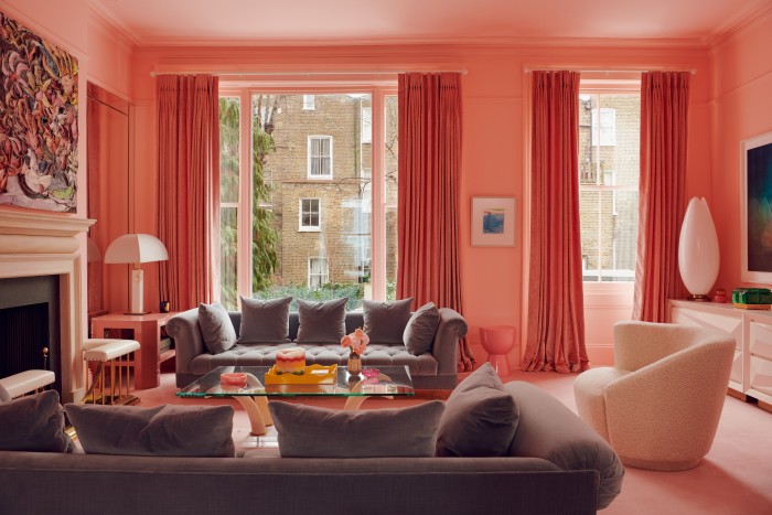 The “shrimp-pink” drawing room features a Nicolas Holiber oil painting over one of a pair of fireplaces from Jamb. The sofas, side lamps and coffee table are all from Talisman