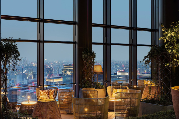 The view over the city from the hotel’s top floor, from a candlelit space with rattan chairs, small wooden tables and foliage