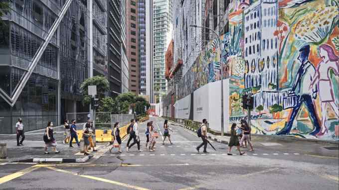 Pedestrians cross a street in Raffles Place in Singapore