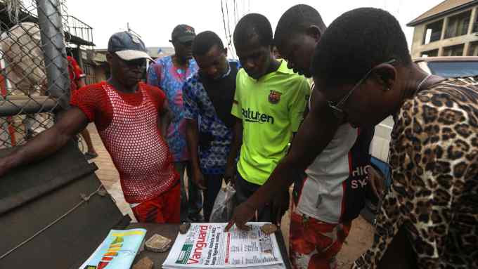 People discuss the election at a newspaper stand in Awka, Nigeria, on Monday