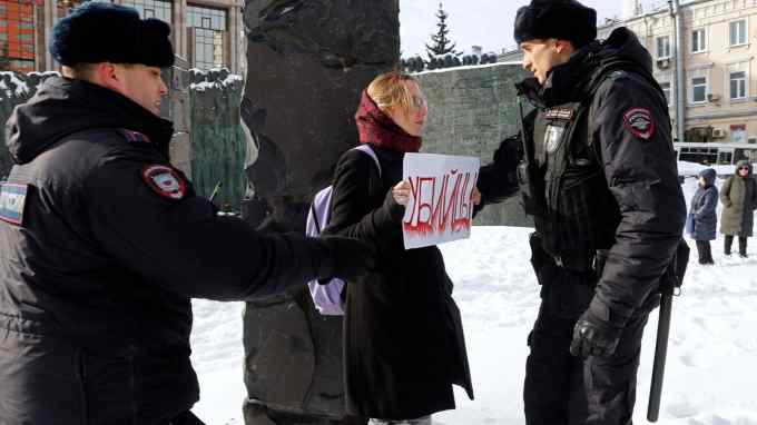 Police officers detain a woman with a placard reading “Murderers” during a gathering in memory of Russian opposition leader Alexei Navalny in Moscow