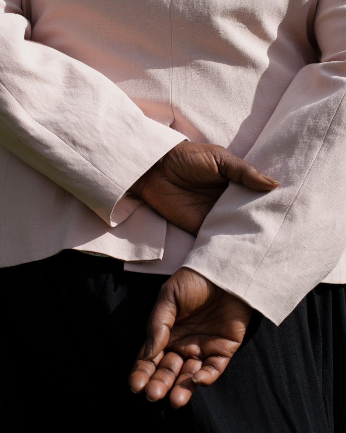A close-up of Mimi’s hands clasped behind her back