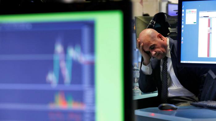 A specialist rests his head in his hand as he works on the floor of the New York Stock Exchange