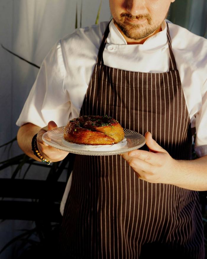 One of Mamakas’ chefs holding a spanakopita on a plate