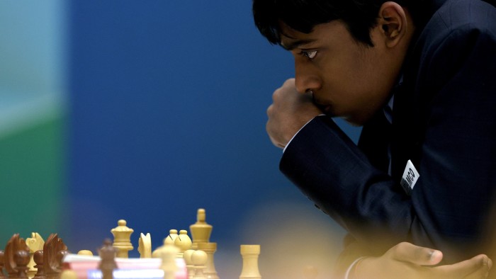 A teenage chess player leans over the board with intense concentration  