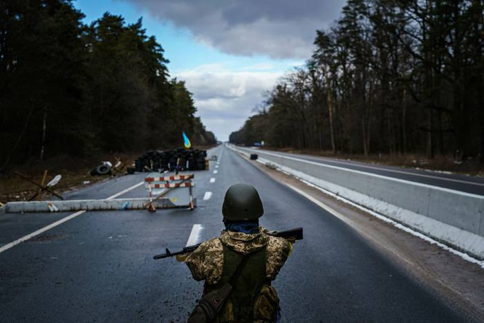 A soldier standing by a checkpoint on a highway