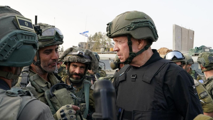 Yoav Gallant wearing a helmet and flak jacket speaks to soldiers