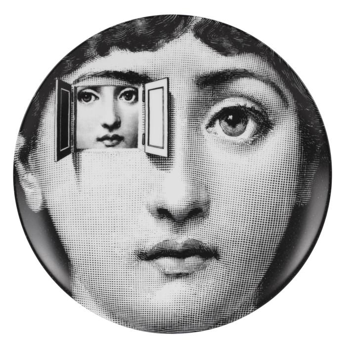 A plate is printed with a black-and-white image of a woman’s face. One of her eyes opens like a door to reveal a smaller image of the same face