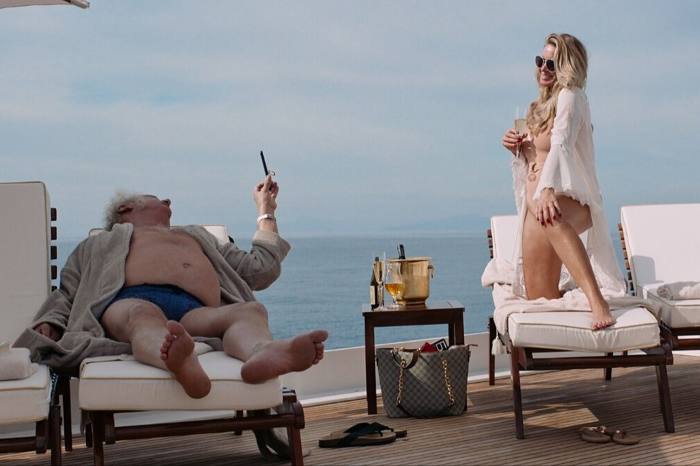 film still from ‘Triangle of Sadness’. an old man and a woman lounging on a cruise ship
