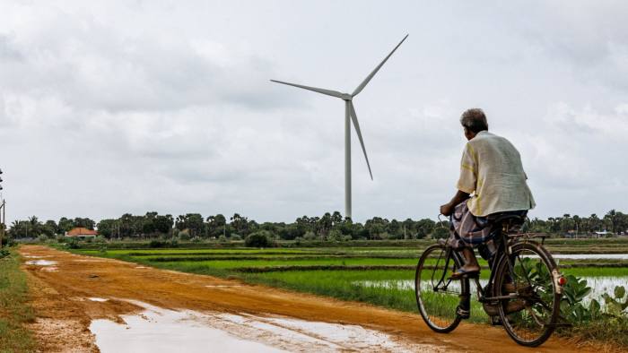 A man on a bicycle passes a wind turbine