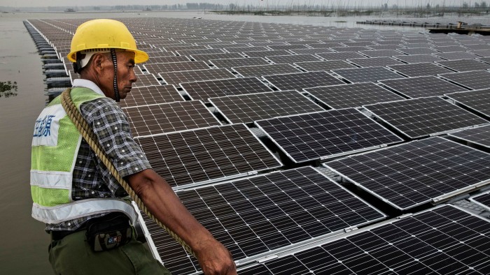 A Chinese worker pulls floating panels that are part of a large floating solar farm project under construction