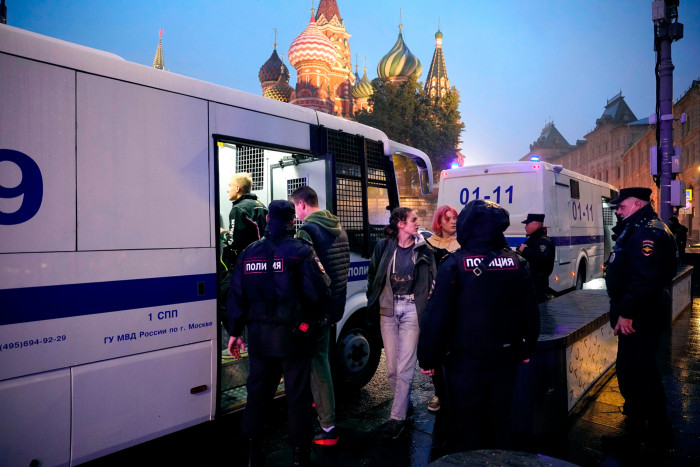 Police officers escort detained demonstrators on to a police bus during a protest in Red Square on Saturday
