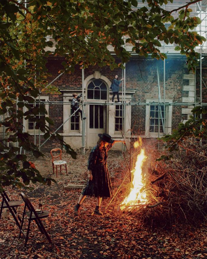 Wilson tending a fire in the walled garden – her children George and Olive are on the scaffolding in front of the rear Palladian façade