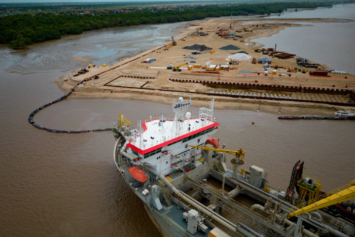 A ship extracts offshore sand to create a coastal port for offshore oil production