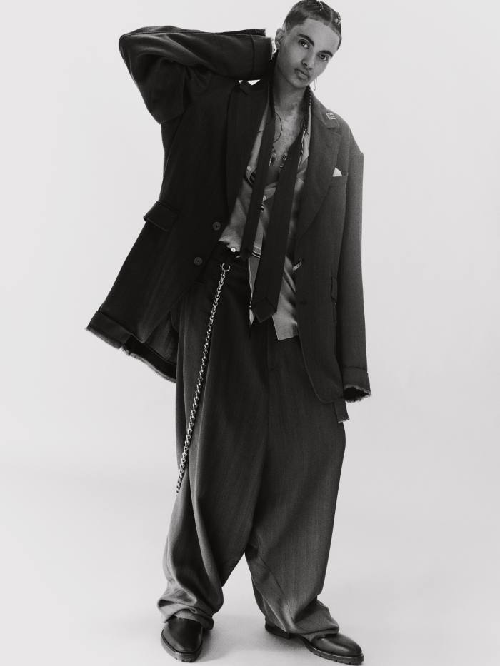 Zaïr wears Maison Mihara Yasuhiro wool-mix blazer, £697, matching trousers, £440, and cupro and rayon shirt, £544. Balenciaga silver-brass trouser chain, £6,390. Dries Van Noten leather shoes, £445. Carrey Paris silver Skyler XL earring, €25
