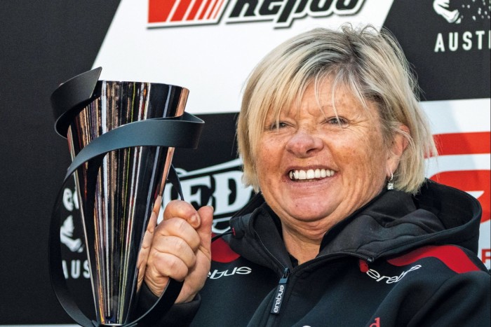 A woman smiling as she’s holding a racing trophy
