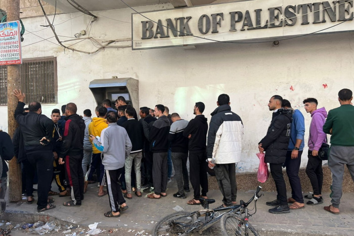 People queue at a cash machine at a branch of the  Bank of Palestine