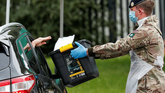 A member of the UK armed forces takes a completed Covid-19 test from a driver at a mobile testing centre in Leicester in June