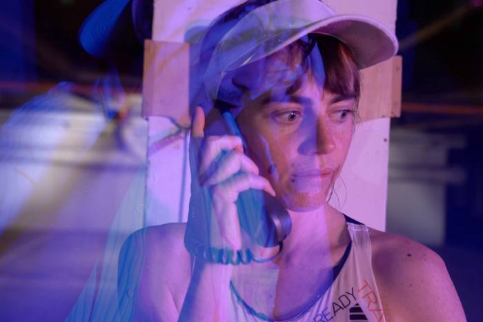 A person in a running top on an old-fashioned phone seen through a purple filter