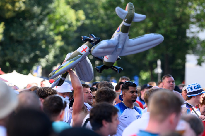 A crowd of supporters, one of whom holds aloft an inflated model aircraft