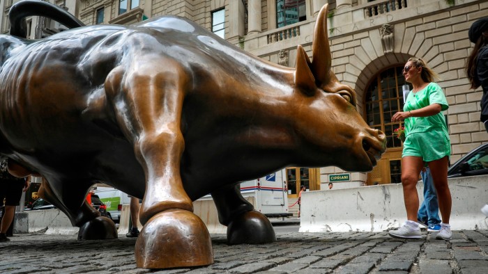 Tourists visit the Wall Street bull statue
