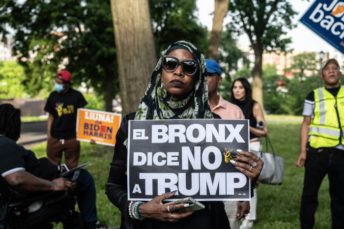 A protester holds a sign reading “El Bronx dice no Trump”