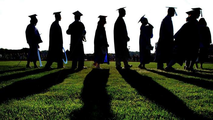 Graduates march onto grassy field during graduation ceremony