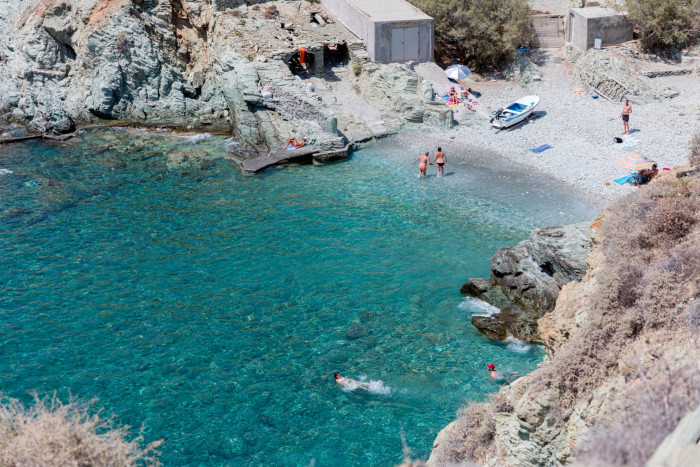 People swim in the clear blue waters of a cove