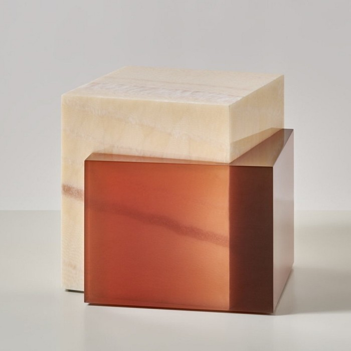 A large creamy cube has a small clear brown cube emerging from it at an angle