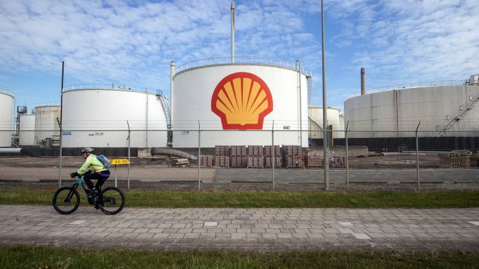 A cyclist passes oil silos at a Shell refinery in Rotterdam