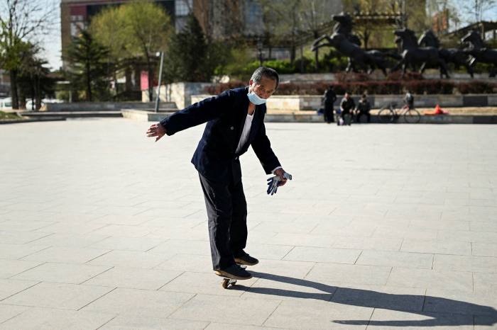 An elderly man balances on roller skates