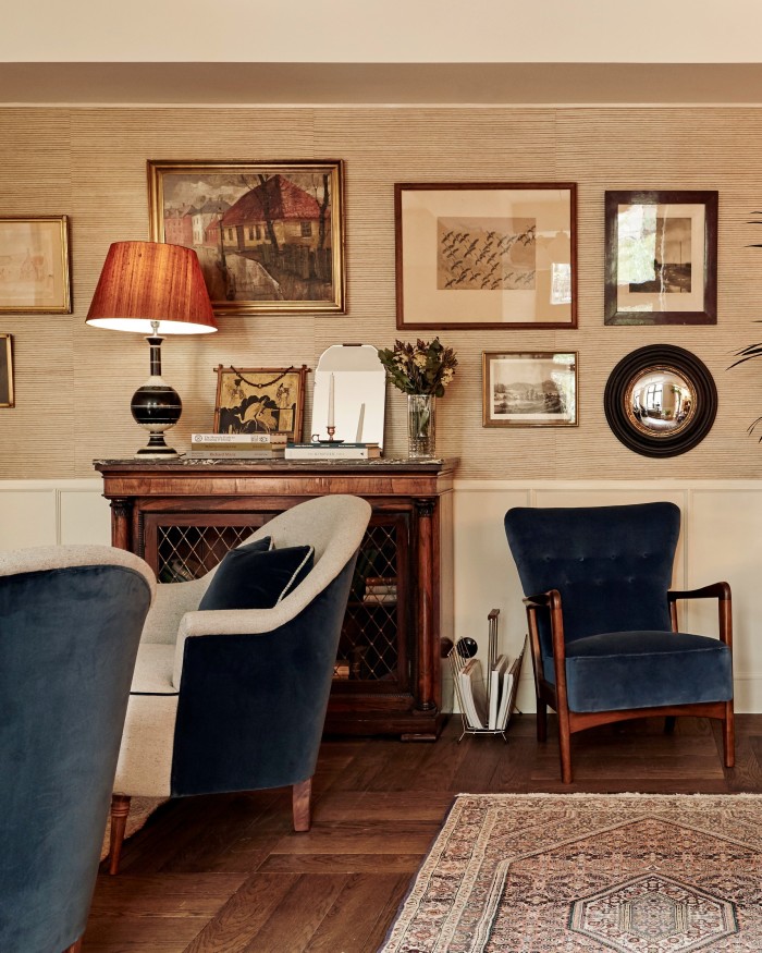 Blue and white armchairs in front of a glass-fronted wooden book cabinet in Hotel Sanders’ living room