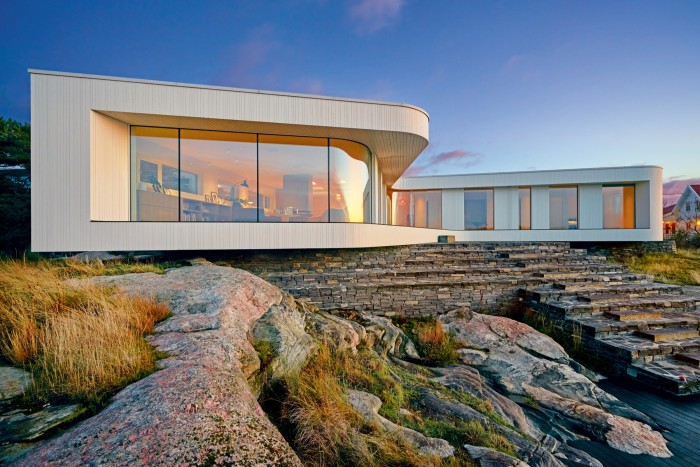 Villa AT by Saunders Architecture is perched on stone steps leading down to the water