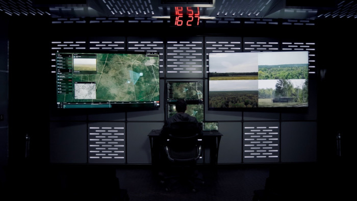 Person looks at computer screens showing military operations