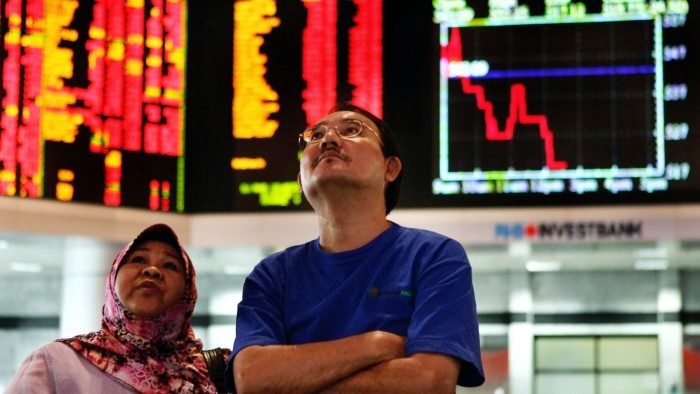 A couple looks at share prices at a private stock market gallery in Kuala Lumpur, Malaysia