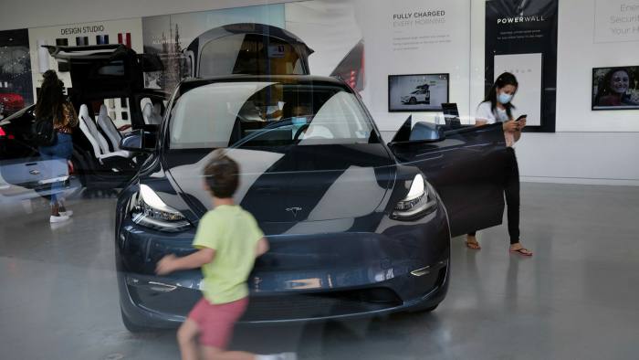 A woman and boy looking at a Tesla electric car in a showroom