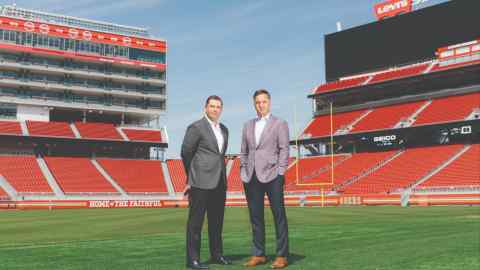 Two men in suits standing in the middle of an empty football stadium