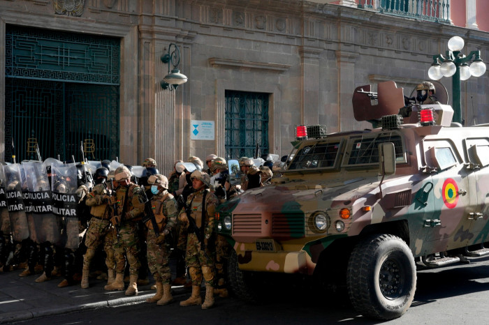 An armored vehicle and military police form outside the government palace at Plaza Murillo in La Paz