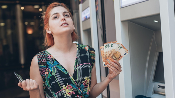A teenager holding banknotes and a credit card 