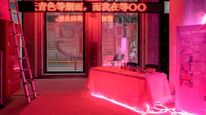 A room with a table covered in a white cloth lit in pink neon