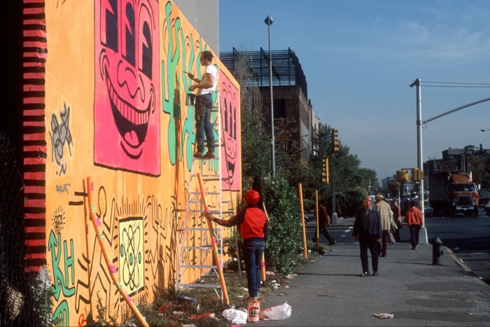 Haring painting a mural in the Bowery, New York, in 1982