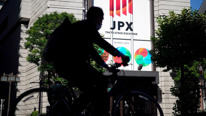 A cyclist passes the Tokyo Stock Exchange