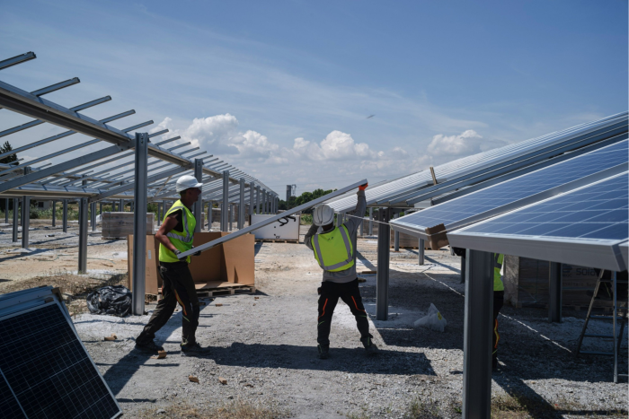Workers install solar panels at the Renewable Energy Systems Ltd. solar park