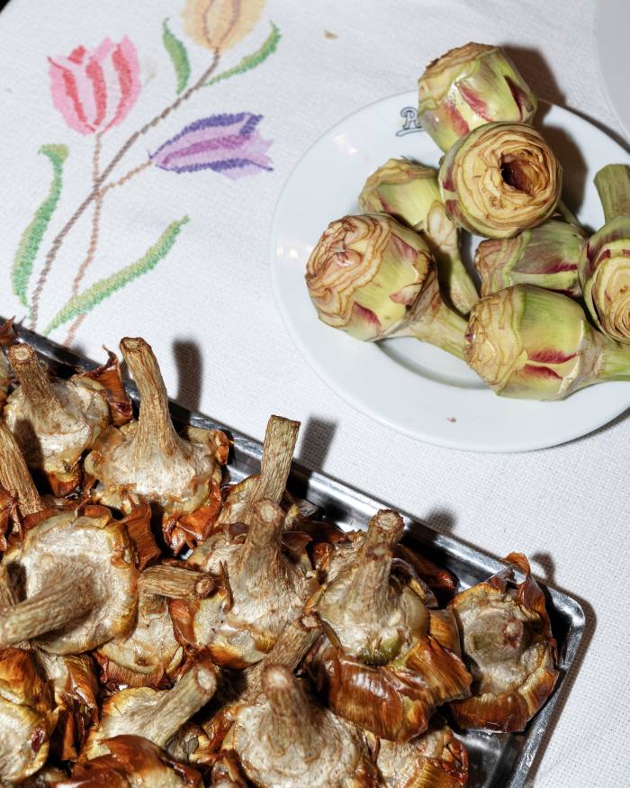 Cooked artichokes in a metal tray and on a plate a Pecorino