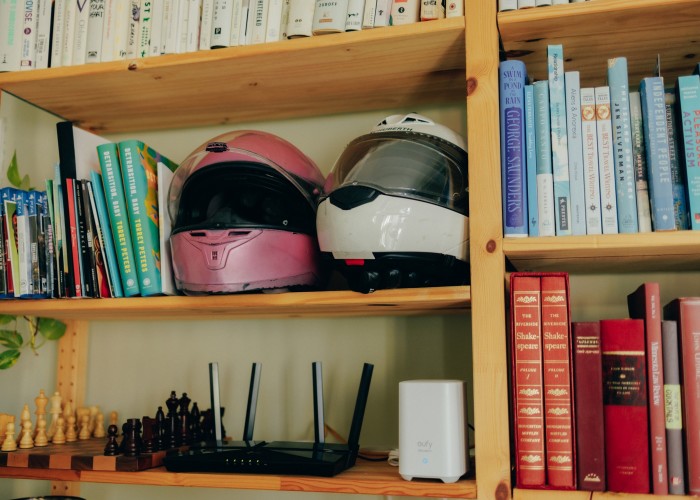 A pair of helmets alongside books and games on Torrey Peters’ shelves