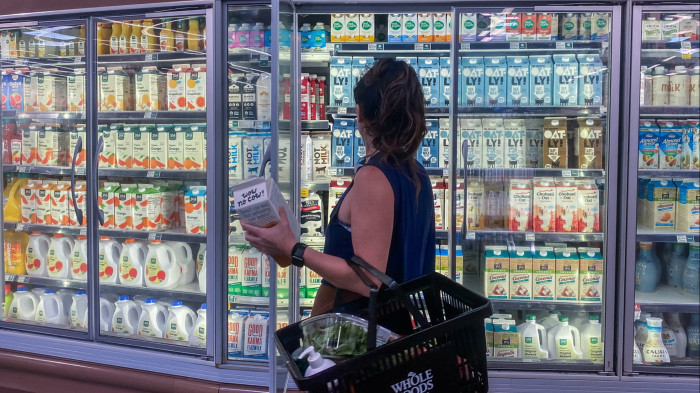 A woman taking milk out of a fridge in a shop
