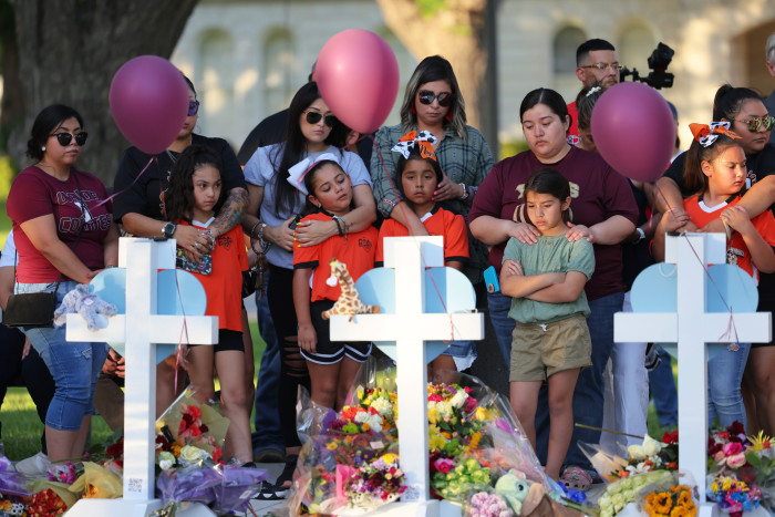 People look at three crosses marking a memorial for victims of the Uvalde school shooting